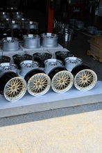 Load image into Gallery viewer, 20" BBS LM471/LM472 wheels in gold finish, designed for Porsche 991 fitment, displayed in a warehouse setting.