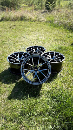 Set of 18-inch BBS RI-A wheels in diamond black finish on grass, showcasing concave design and lightweight forged construction.