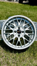 Load image into Gallery viewer, 16-inch BBS RG-F silver wheel with black and gold logo, ideal for E30 BMWs, 4x100 lug pattern, on grass background.
